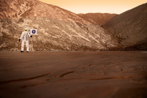 未知の惑星の土に旗を掲げている男性宇宙飛行士