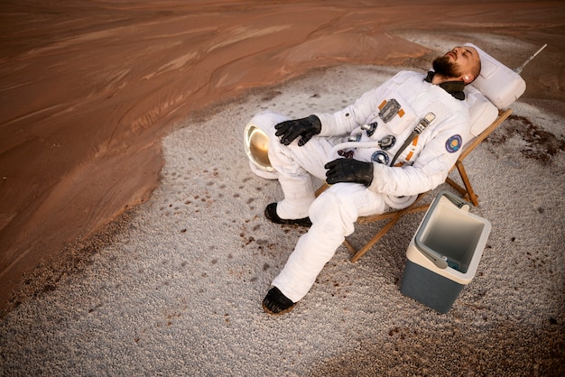 무료 사진 미지의 행성에서 우주 임무를 수행하는 동안 휴식을 취하는 남성 우주비행사