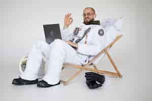 Free photo male astronaut showing the okay sign while working on laptop