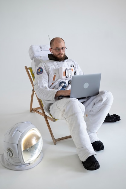 Бесплатное фото Мужчина-космонавт работает на своем ноутбуке в скафандре