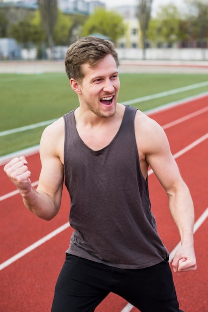 Free photo male athlete celebrating his victory on race track