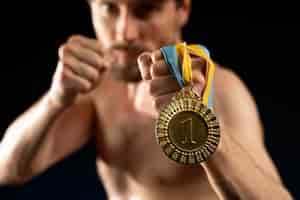 Foto gratuita atleta maschio che tiene una medaglia d'oro