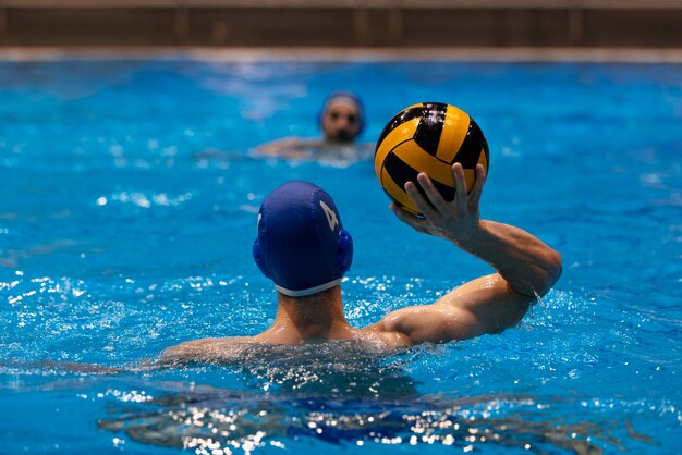 Male athlete playing water polo in indoor pool
