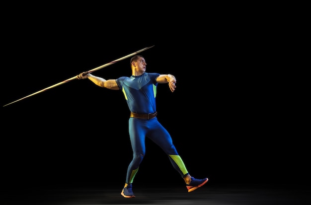 Male athlete practicing in throwing javelin in the dark 