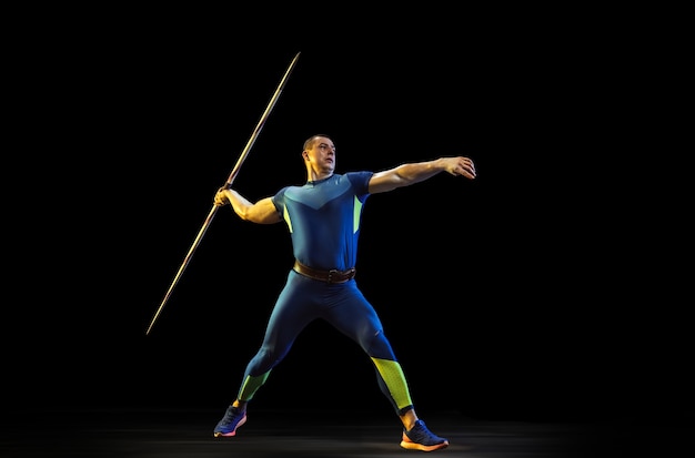 Male athlete practicing in throwing javelin in the dark