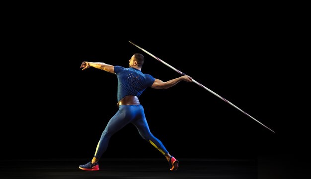 Male athlete practicing in throwing javelin in the dark