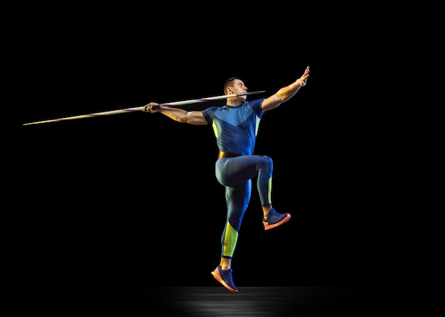 Male athlete practicing in throwing javelin in the dark