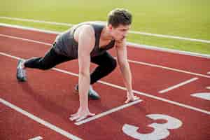 Foto gratuita atleta maschio pronto per iniziare la gara sulla pista di atletica