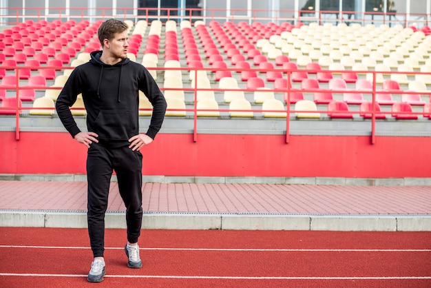 A male athlete standing in front of bleacher exercising