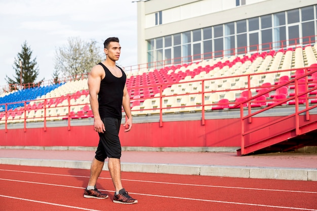 A male athlete standing in front of bleacher on race track