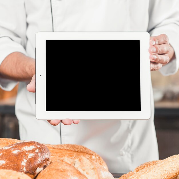 Male baker holding blank digital tablet with baked breads