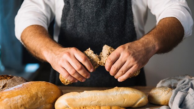 Male baker holding freshly baked bread in the bakery