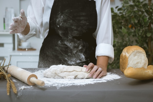 Male baker prepares bread with flour