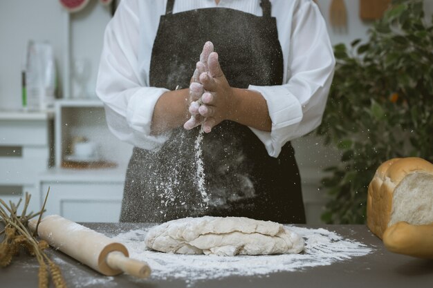 Male baker prepares bread with flour