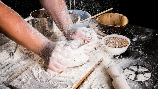 Рука мужского пекаря, замешивающая тесто на кухонном столе