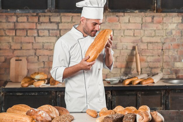 Male baker smelling baked bread loaf