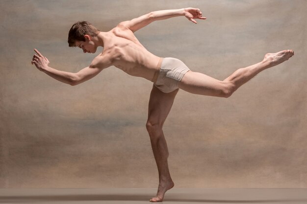 The male ballet dancer posing over gray space