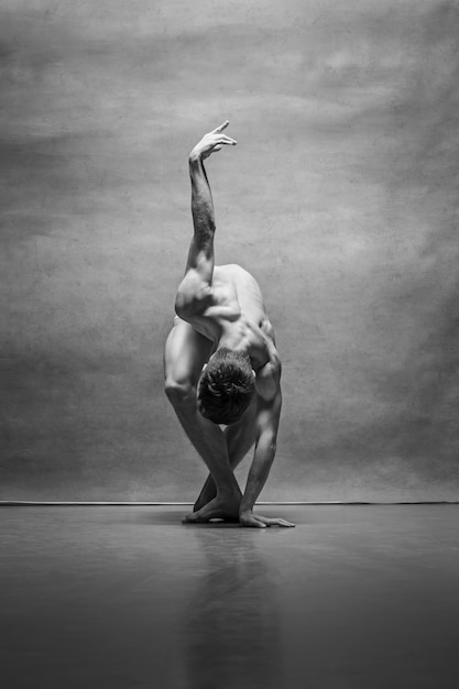 Il ballerino di balletto maschio che posa sopra il gray