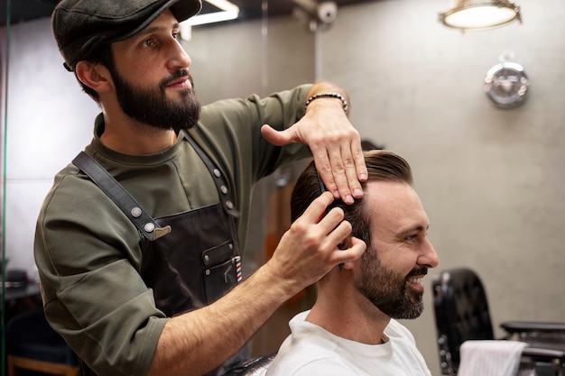 Foto gratuita barbiere maschio che aggiusta i capelli del suo cliente