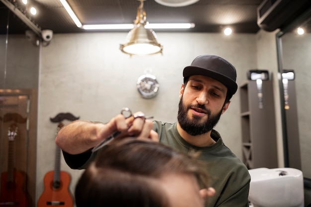 Foto gratuita barbiere maschio che fa un bel taglio di capelli al suo cliente