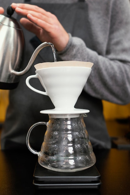 Male barista pouring water in coffee filter