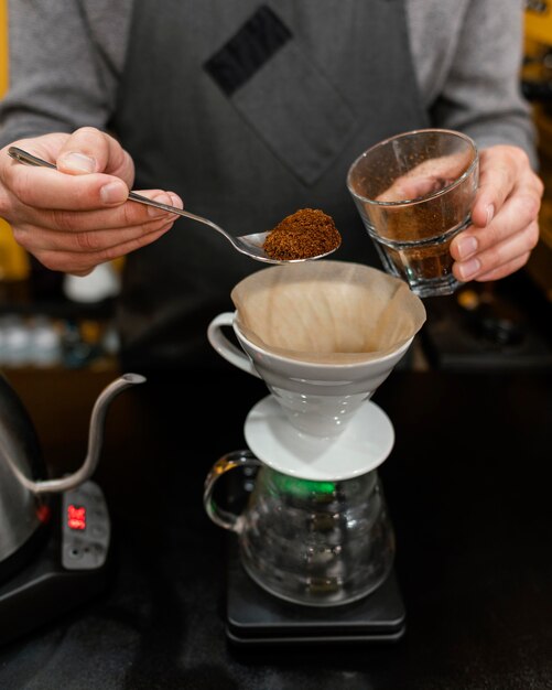 Male barista putting coffee in filter