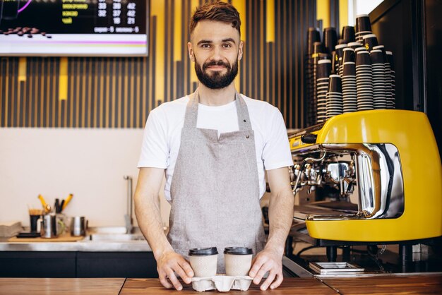 Male barista serving coffee in cardboard cups