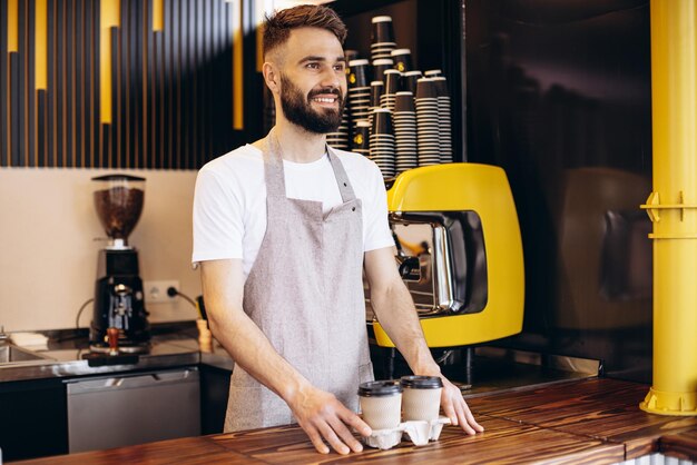 板紙のカップでコーヒーを提供する男性のバリスタ