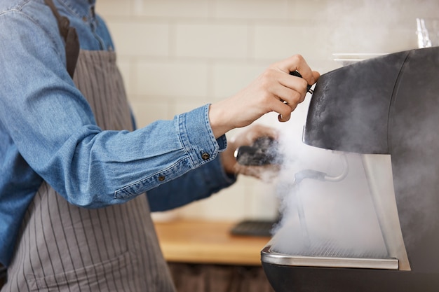 Free photo male barista in uniform washing brewing gadgets using steamer.