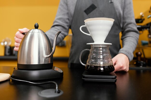 Male barista with apron and kettle