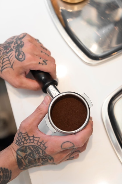 Male barista with tattoos preparing coffee for the coffee machine