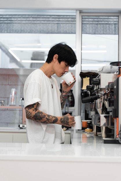 Male barista with tattoos smelling freshly grounded coffee in the cup