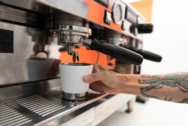 커피 머신을 사용하여 직장에서 문신을 한 남성 바리스타