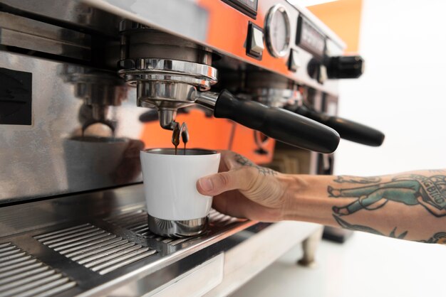 Male barista with tattoos at work using the coffee machine