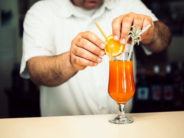 Male bartender decorating exotic cocktail