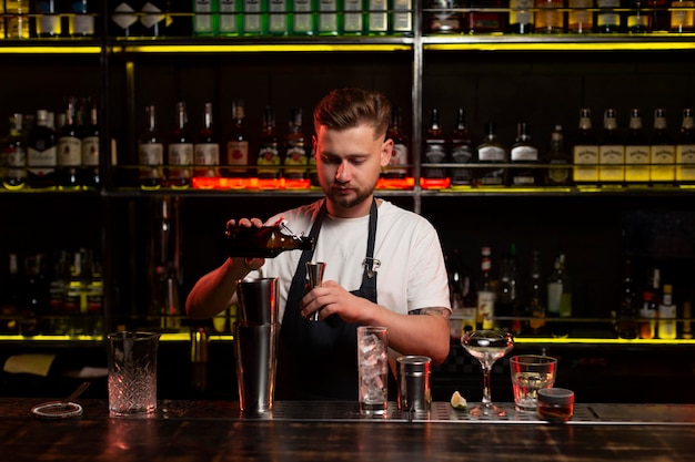 Бесплатное фото Мужчина-бармен делает коктейль с шейкером