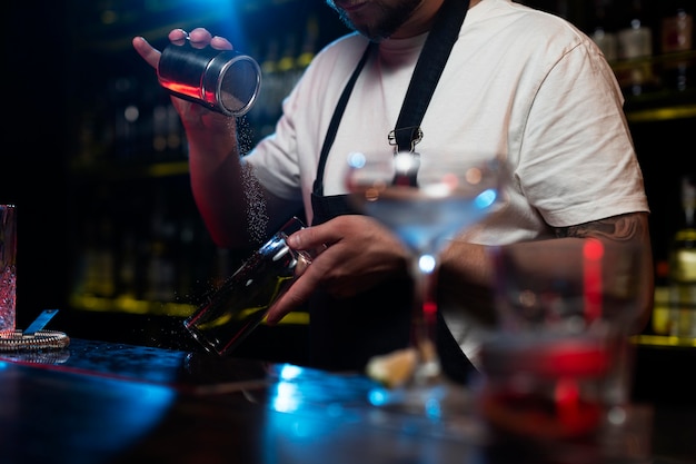 Free photo male bartender making a cocktail with a shaker