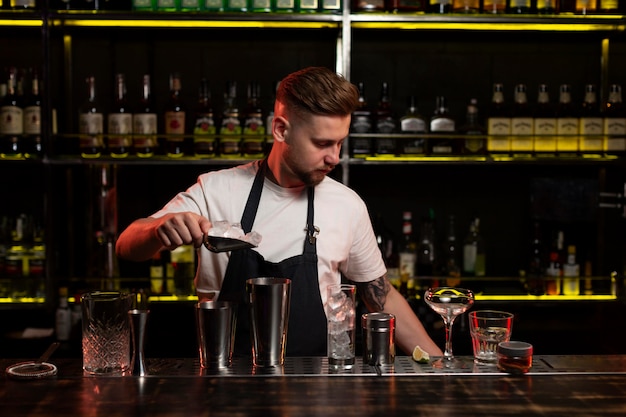 Male bartender making a cocktail with a shaker