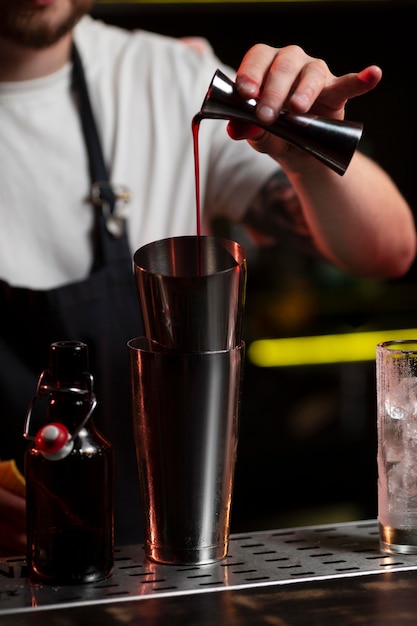 Мужчина-бармен делает коктейль с шейкером
