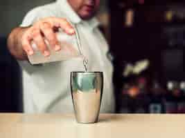 Foto gratuita barista maschio che mescola cocktail in agitatore