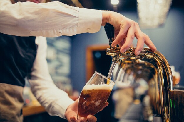 Мужской бармен наливает пиво в пабе