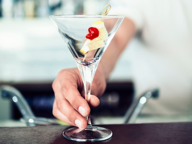 Male bartender serving cocktail with fruits