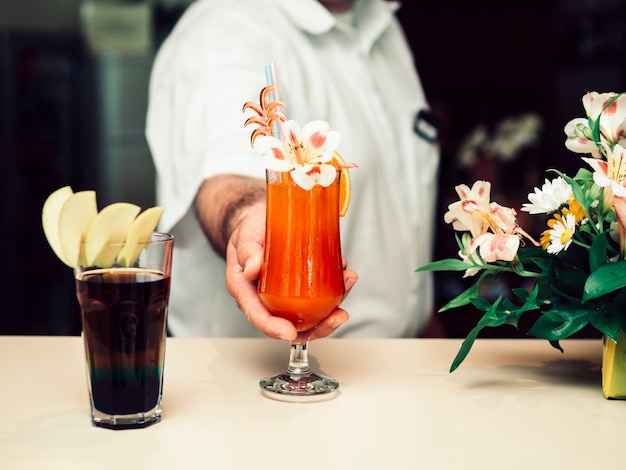 Free photo male bartender serving colourful decorated drink