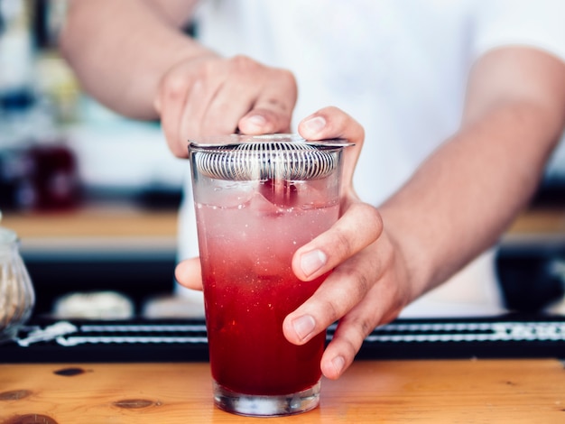 Free photo male bartender using cocktail strainer