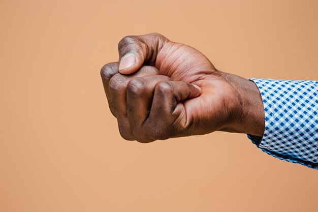 Male black fist isolated on brown. African american clenched hand, gesturing up