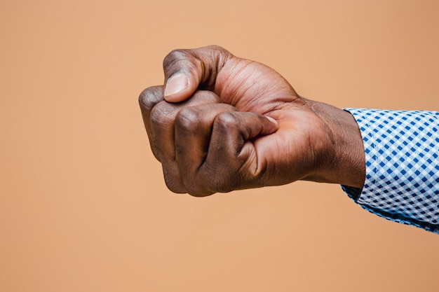 茶色に分離された男性の黒い拳。アフリカ系アメリカ人の握り手、身振りで示す