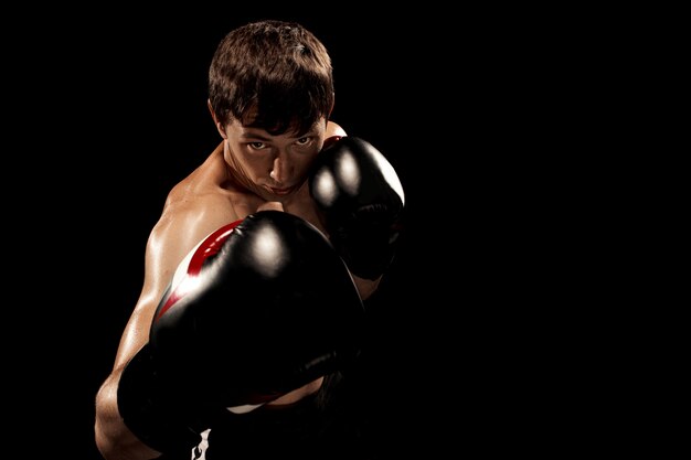 Male boxer boxing in punching bag with dramatic edgy lighting