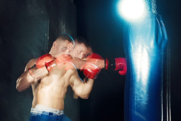 Male boxer boxing in punching bag