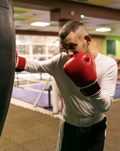 Боксер мужского пола тренируется с боксерской грушей