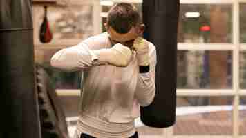 Free photo male boxer practicing with punching bag